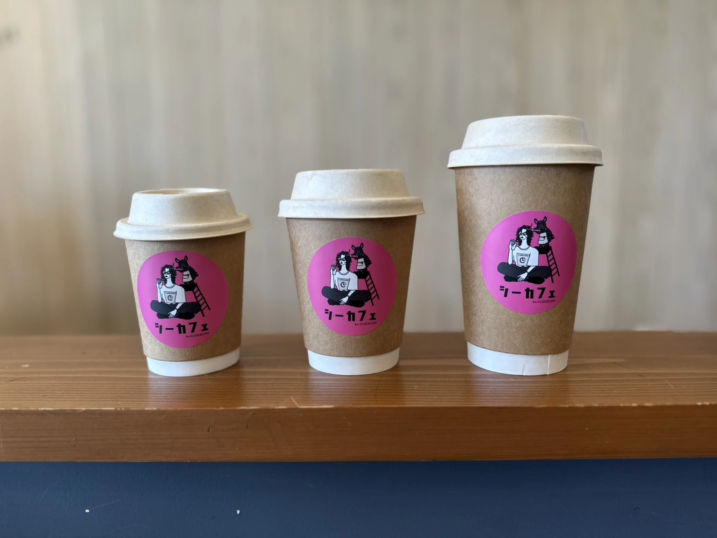 ピンクのロゴが入ったシーカフェのテイクアウトカップ