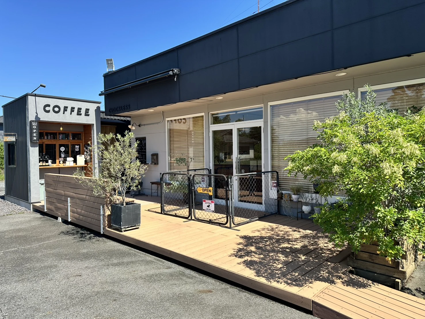 COFFEEの看板とウッドデッキがあるCLOCKLESSとシーカフェの外観